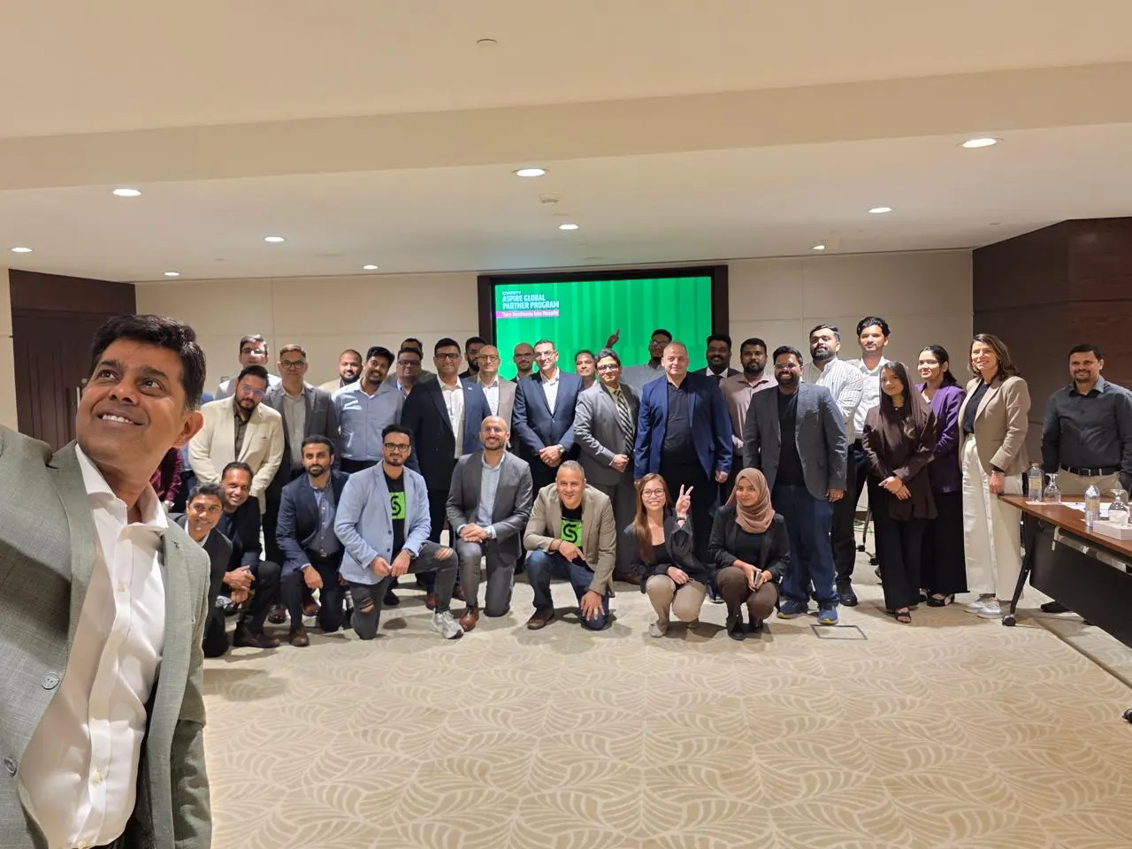 Group photo of Cohesity, VAD Technologies and partner teams in front of the Cohesity Aspire Global Partner Program slide, Metropolitan Hotel Dubai